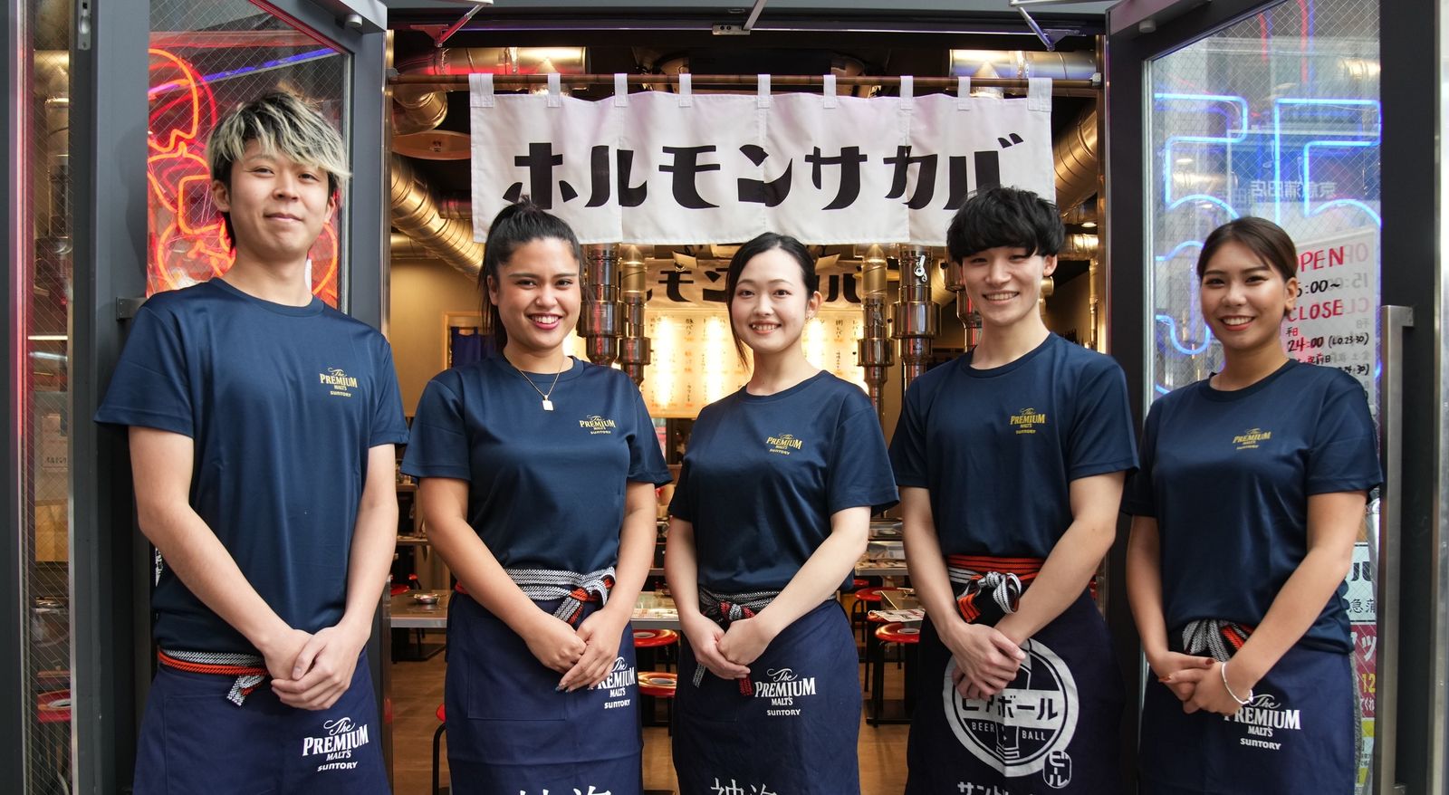 ホルモンサカバの看板の前に並ぶスタッフ